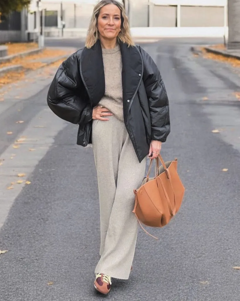 Nice Fall Outfits 2026 Black Puffer Over a Beige Knit Set With a Tan Tote