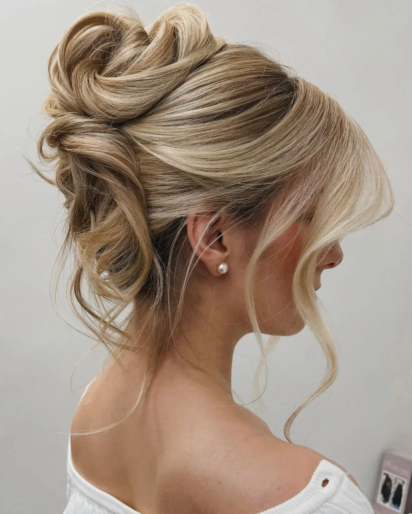 Fall Hairstyles for Office 2026 Voluminous Messy High Bun with Soft Blonde Movement
