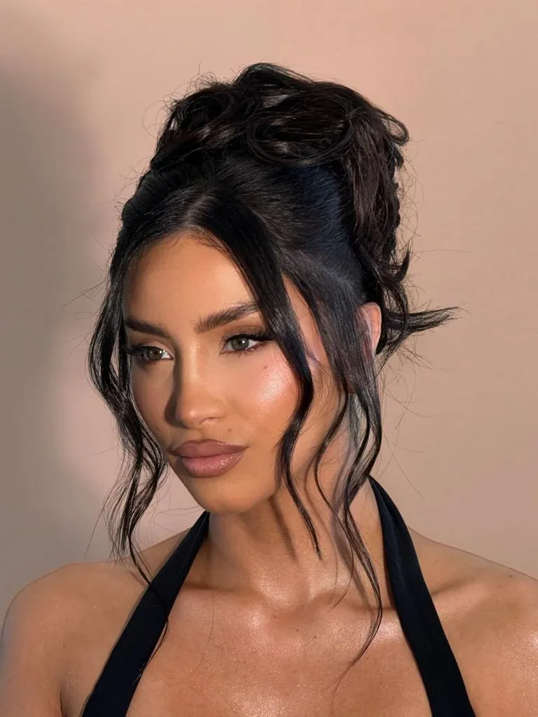 Fall Hairstyles for Wedding Guests 2026 Dark Textured Top Knot with Soft Face-Framing Tendrils