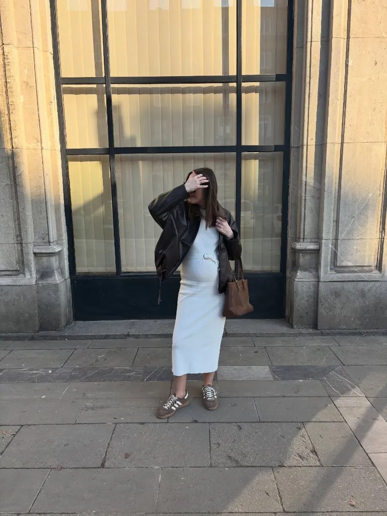 Fall Pregnancy Outfits 2026 Ivory Midi Dress With a Brown Leather Jacket and Adidas Sambas
