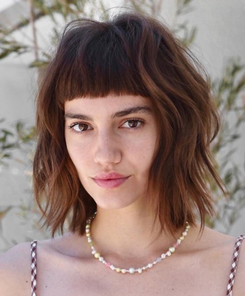 Medium shaggy bob haircut with short blunt bangs and razored layers