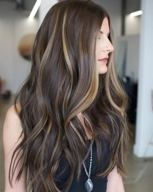 Blonde balayage partial highlights on brown hair in beachy waves