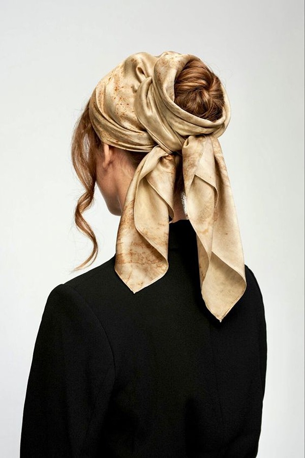 Woman wearing a silk square scarf wrapped around her hair