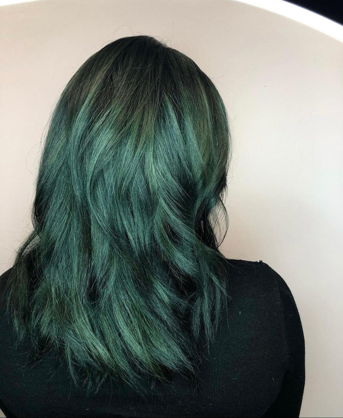 Teal money piece highlights framing the face on brunette hair