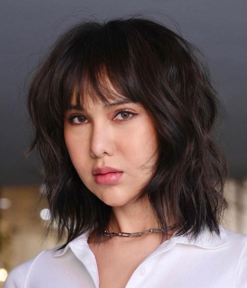 Medium shaggy haircut with wispy bangs on dark brown hair
