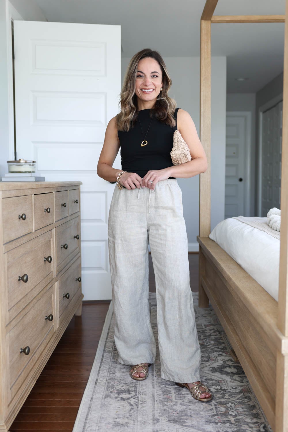 Relaxed linen trousers styled with a fitted black boatneck top and sandals.
