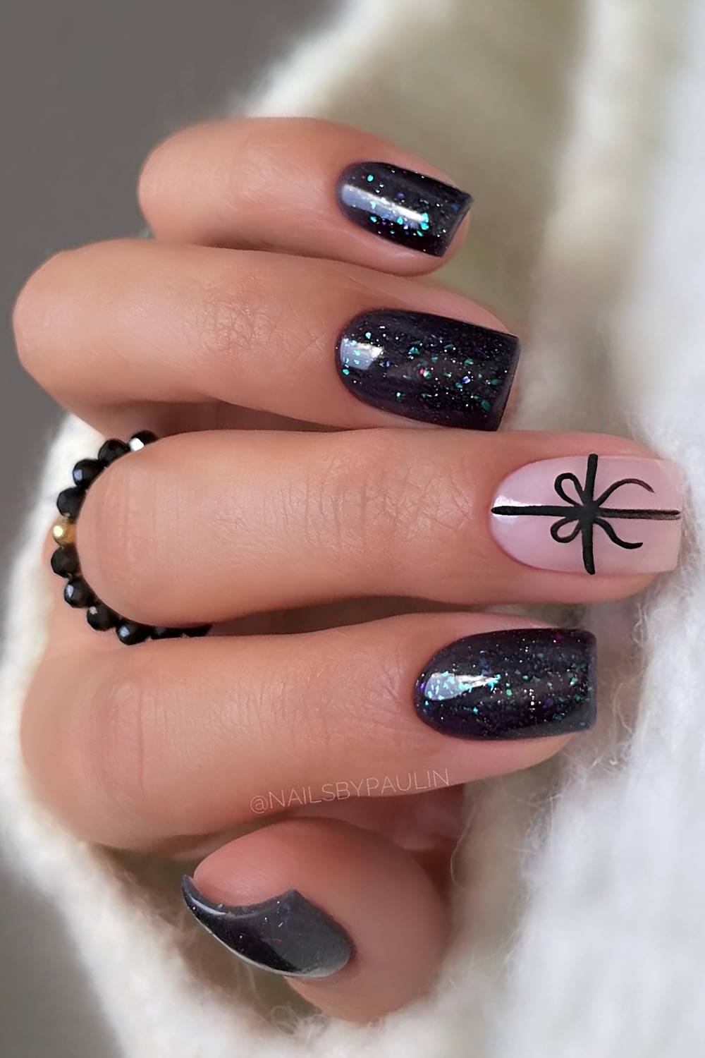 Shimmering Black Nails with a Small White Bow Accent black Christmas nail design