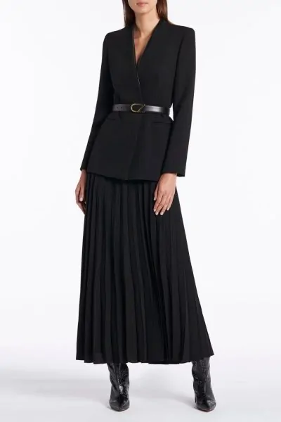 Black blazer cinched at the waist with a belt over a pleated skirt