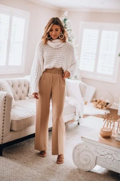 Loose white sweater partially tucked into high-waisted trousers