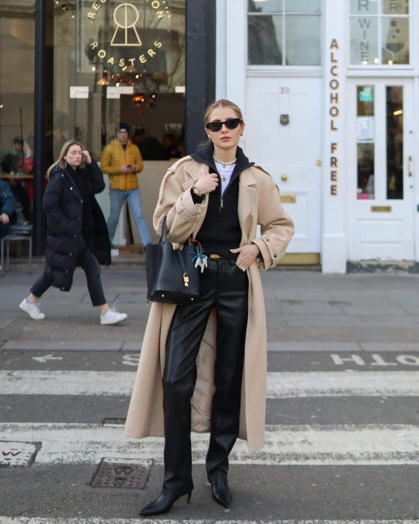 Black leather trousers worn with a black top under a long cream coat