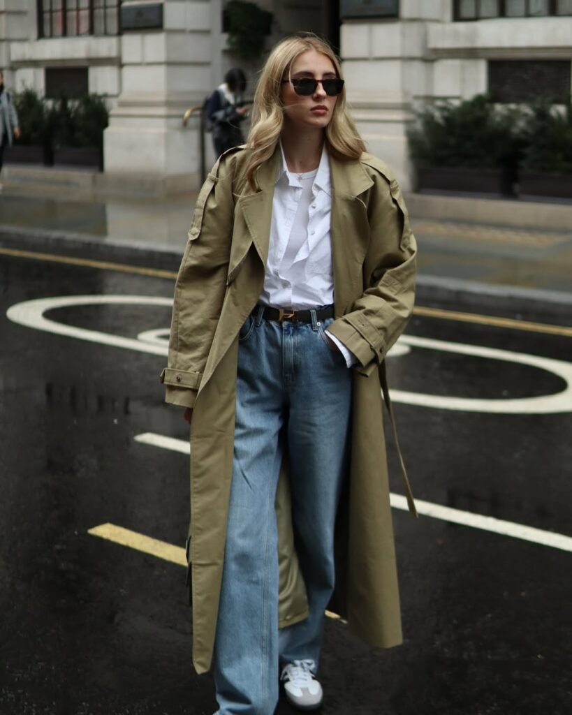 Olive trench coat over a white shirt and wide-leg jeans vintage style outfit