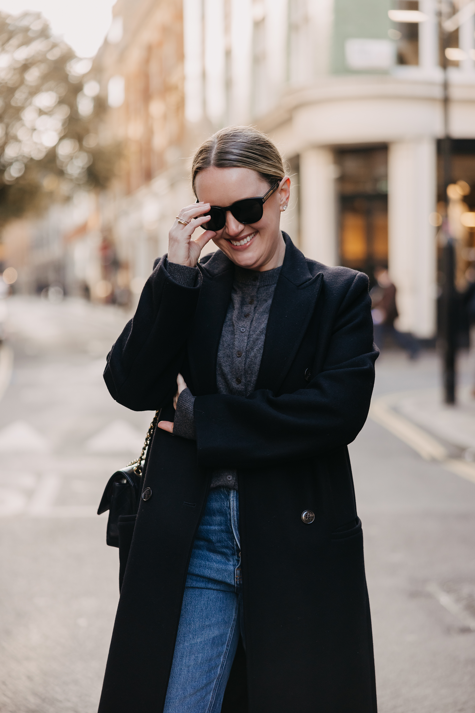 Black wool coat with a grey knit sweater and straight-leg jeans London outfit