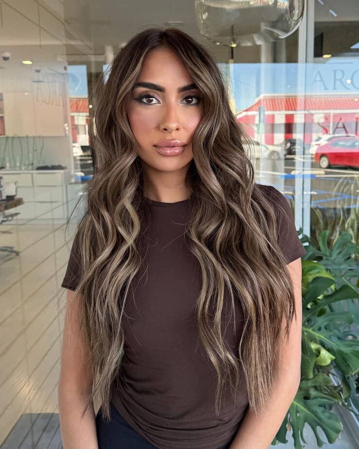 Long ash brown hair in soft waves with face-framing highlights