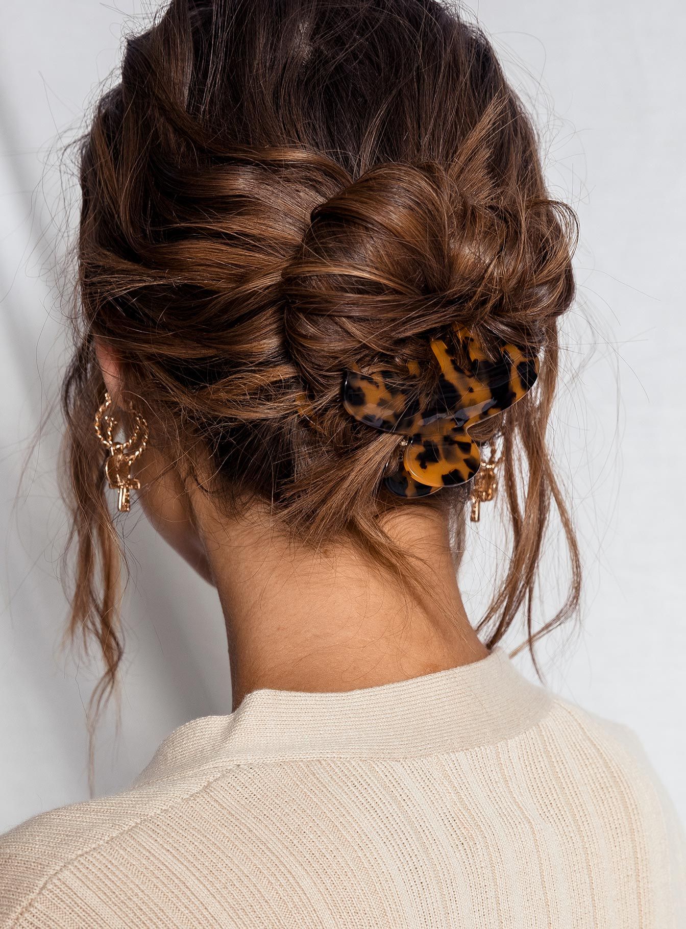 Messy low bun with textured hair secured by a tortoiseshell claw clip
