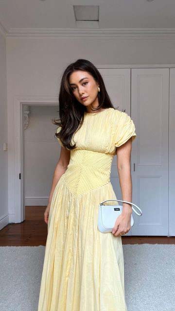 Pale yellow pleated midi dress with a white bag church outfit