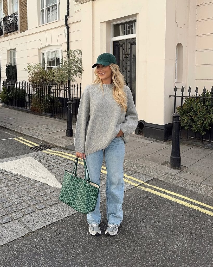 Grey oversized knit sweater with light wash jeans and a baseball cap