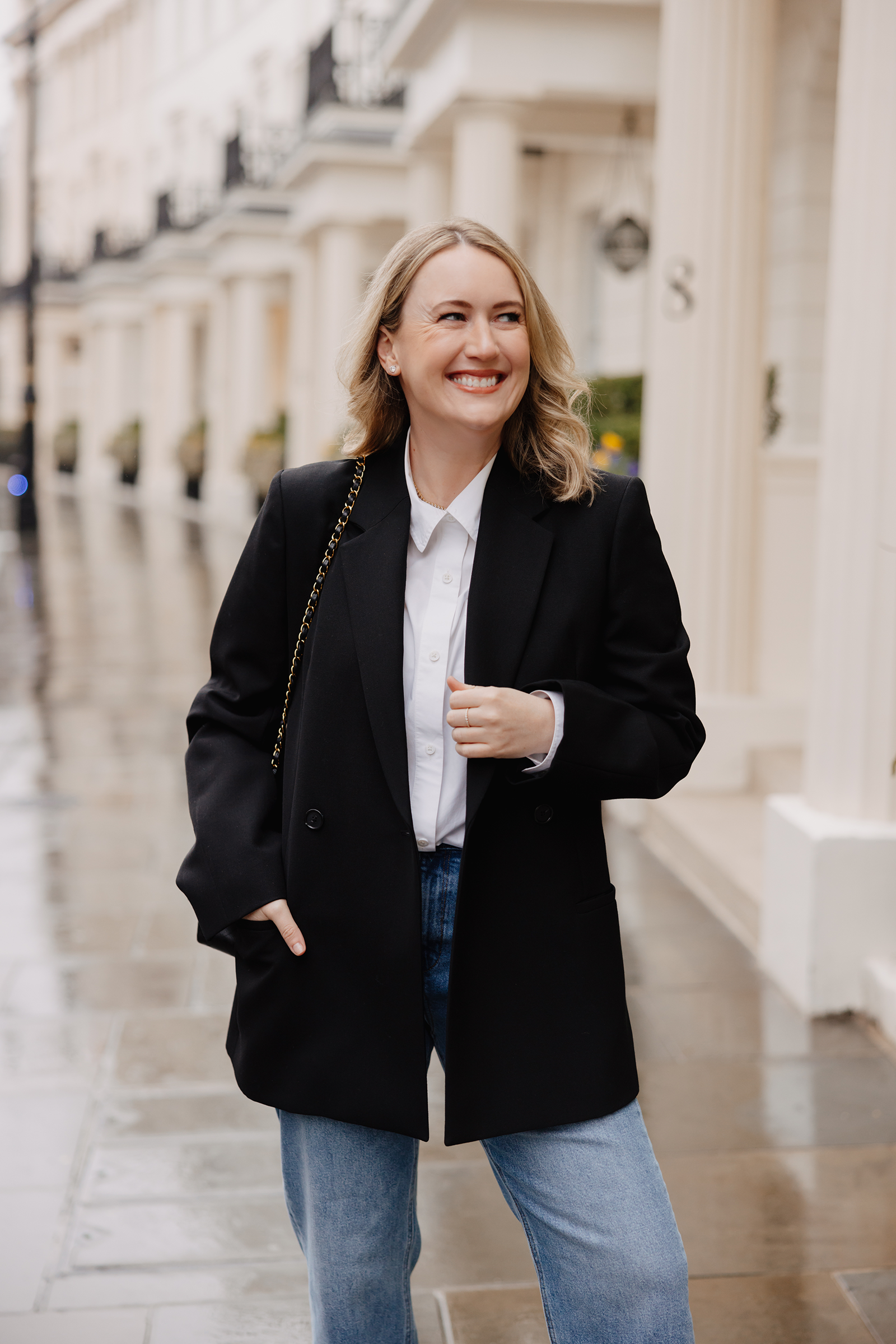 White button-down shirt with a blazer and blue jeans on a rainy London street