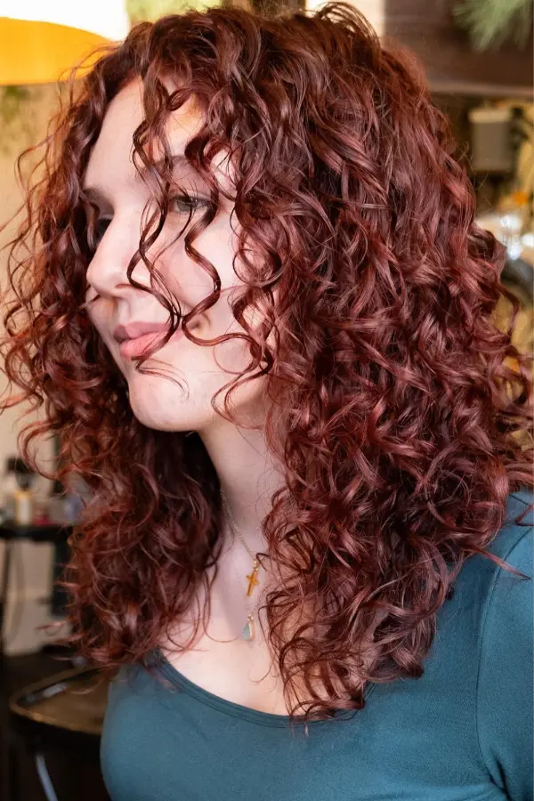 Curly hair in cherry cola red-brown color with defined voluminous curls