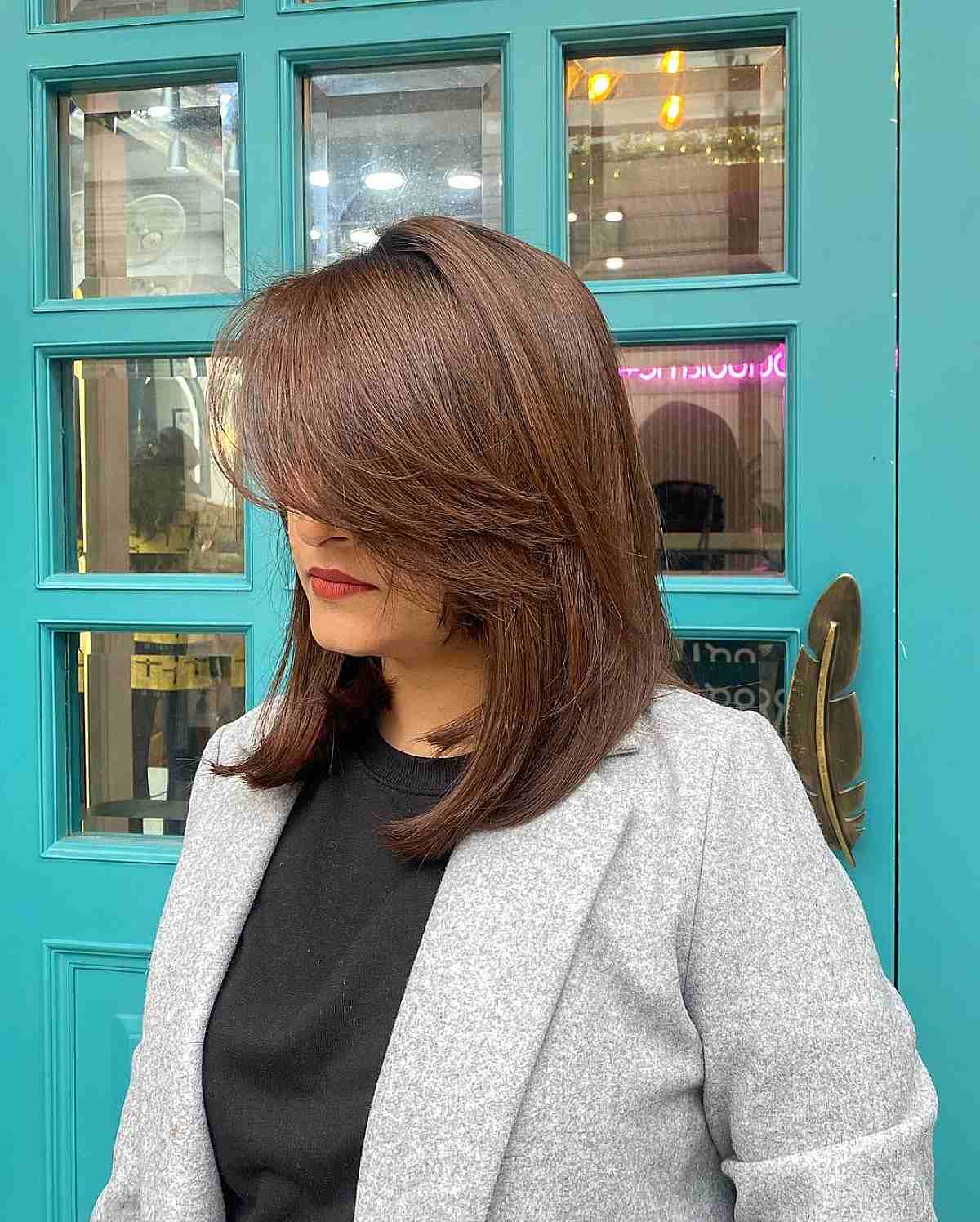 Long bob with side-swept bangs and caramel highlights