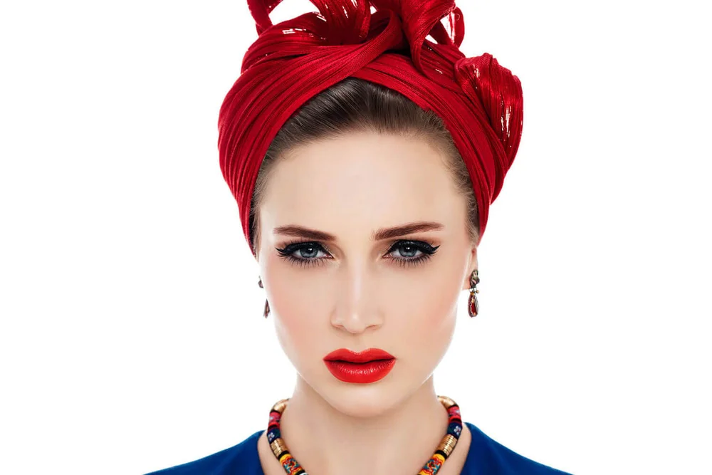 Woman wearing a bold red turban wrap with elegant makeup
