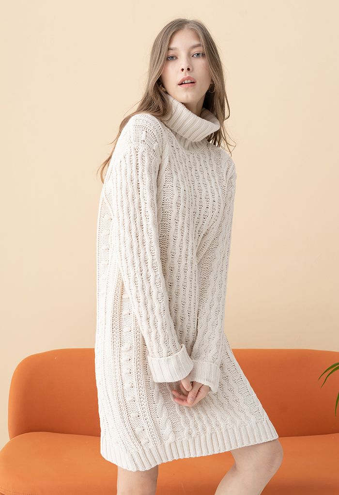 Woman wearing a cream cable-knit sweater dress with a high neckline