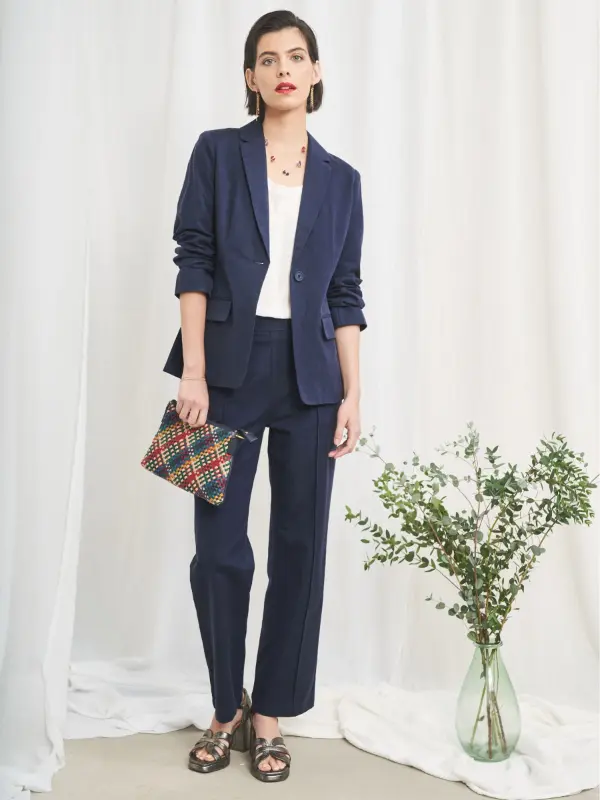 Navy suit with a white top and a woven clutch