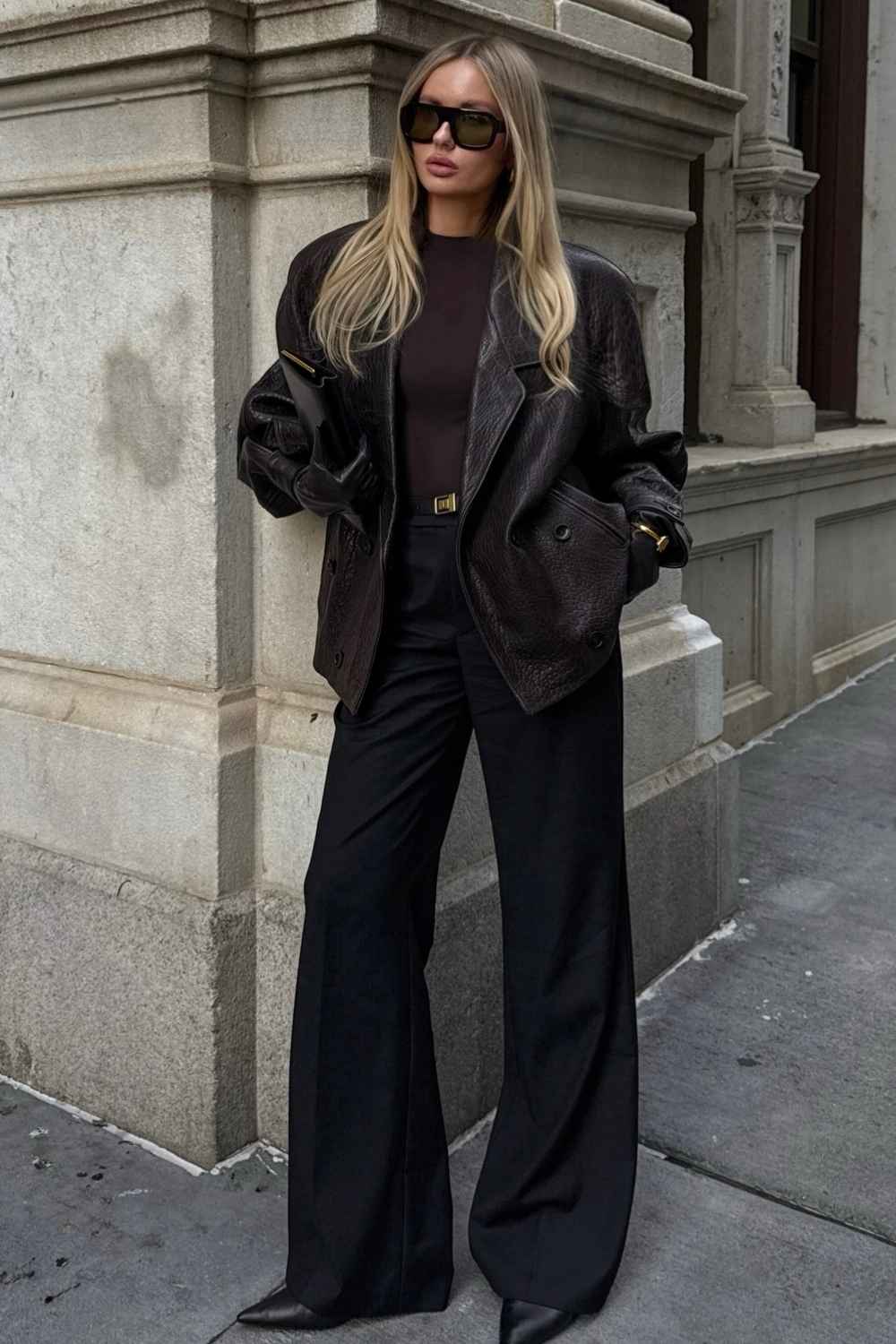 Boxy black leather blazer worn with wide-leg black trousers