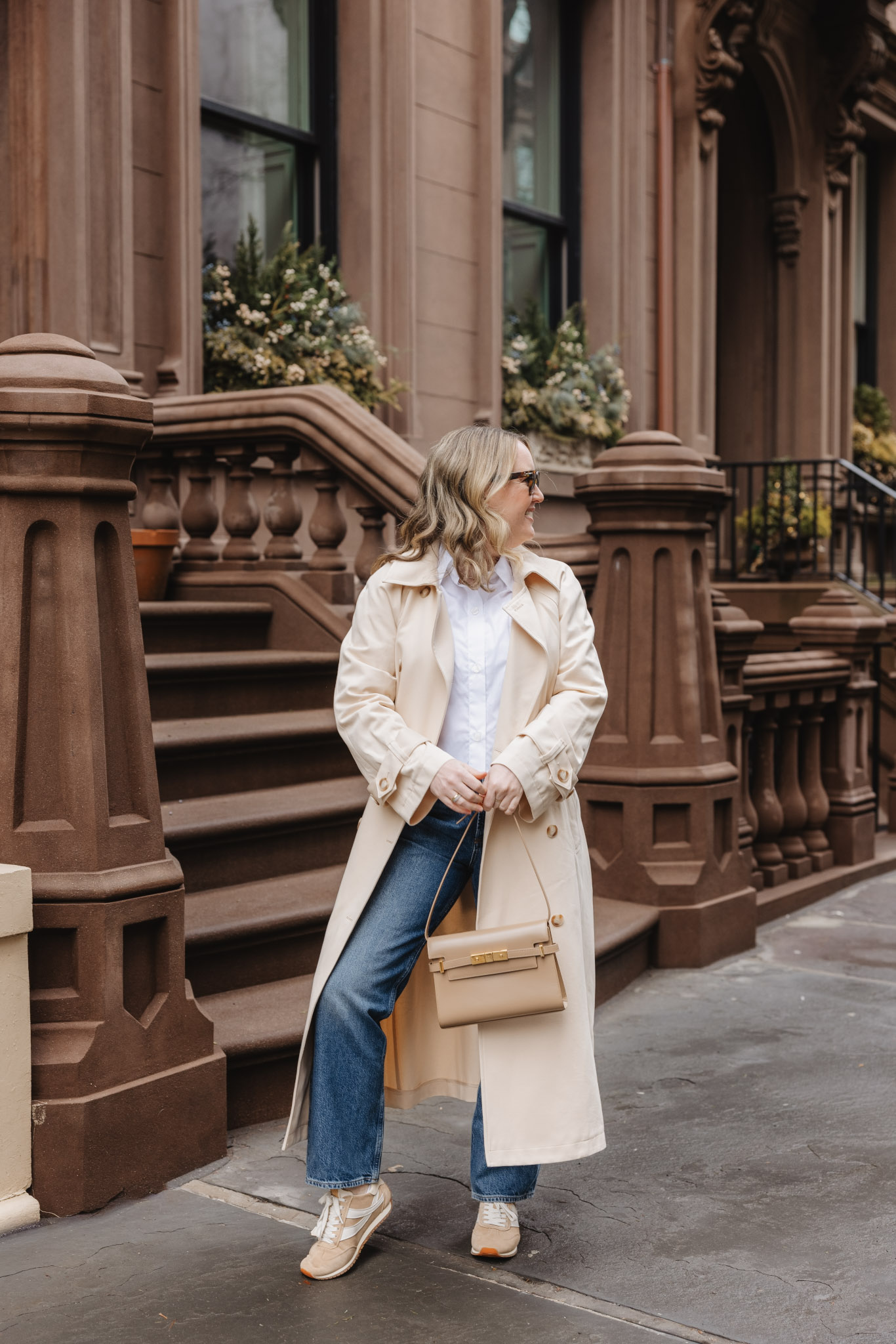 Woman in a trench coat with jeans and sneakers LA outfit