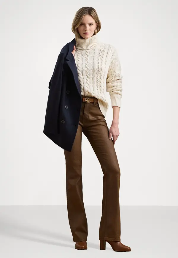 Cream cable turtleneck sweater with brown leather trousers and a navy coat